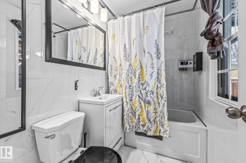 Bathroom featuring vanity, shower / bath combination with curtain, tile walls, and marble look tile flooring - 5911 119 Avenue, Edmonton, AB - Indoor Photo Showing Bathroom