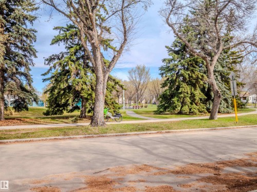 View of asphalt road featuring sidewalks, traffic signs, and curbs - 5911 119 Avenue, Edmonton, AB - Outdoor With View