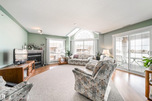 Living area with wood finished floors and a fireplace - 402 7803 Golf Course Road, Stony Plain, AB - Indoor Photo Showing Living Room With Fireplace