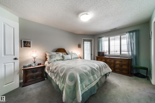 Carpeted bedroom with a textured ceiling and baseboards - 402 7803 Golf Course Road, Stony Plain, AB - Indoor Photo Showing Bedroom