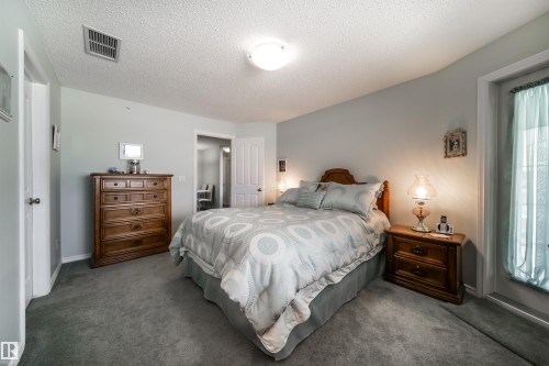 Carpeted bedroom featuring a textured ceiling and baseboards - 402 7803 Golf Course Road, Stony Plain, AB - Indoor Photo Showing Bedroom