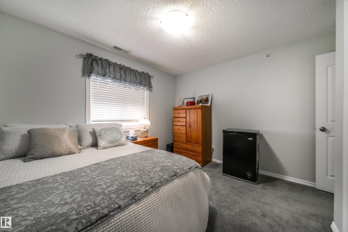 Bedroom featuring a textured ceiling and carpet - 402 7803 Golf Course Road, Stony Plain, AB - Indoor Photo Showing Bedroom