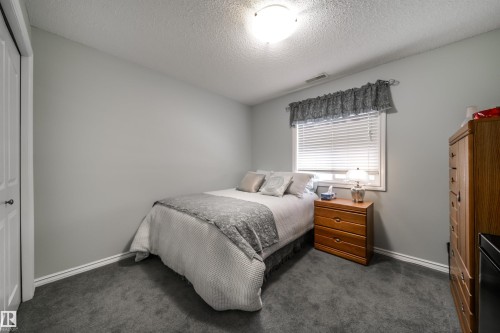 Bedroom featuring a textured ceiling, dark colored carpet, and a closet - 402 7803 Golf Course Road, Stony Plain, AB - Indoor Photo Showing Bedroom
