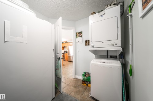 Laundry area with a textured ceiling and stacked washing machine and dryer - 402 7803 Golf Course Road, Stony Plain, AB - Indoor Photo Showing Laundry Room