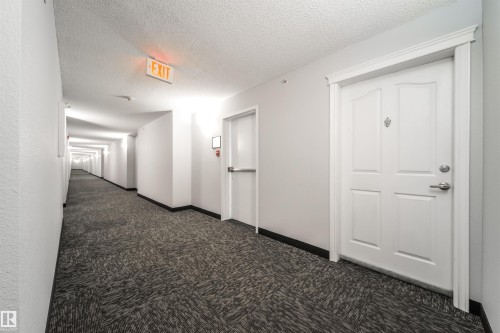 Corridor with dark colored carpet and a textured ceiling - 402 7803 Golf Course Road, Stony Plain, AB - Indoor Photo Showing Other Room