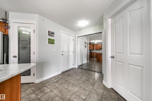 Entryway with a textured ceiling and light tile patterned floors - 402 7803 Golf Course Road, Stony Plain, AB - Indoor Photo Showing Other Room