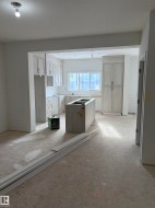 Kitchen featuring a center island, light countertops, light colored carpet, and a textured ceiling - 