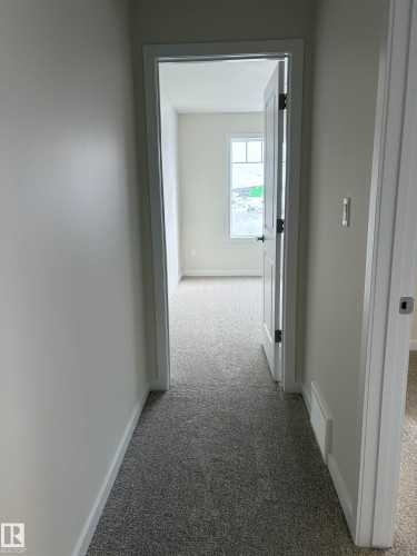 Corridor with light carpet and baseboards - 5756 Hawthorn Common, Edmonton, AB - Indoor Photo Showing Other Room