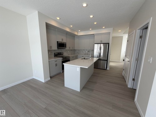 Kitchen featuring stainless steel appliances, an island with sink, gray cabinets, light wood-style floors, and a textured ceiling - 5756 Hawthorn Common, Edmonton, AB - Indoor Photo Showing Kitchen With Upgraded Kitchen