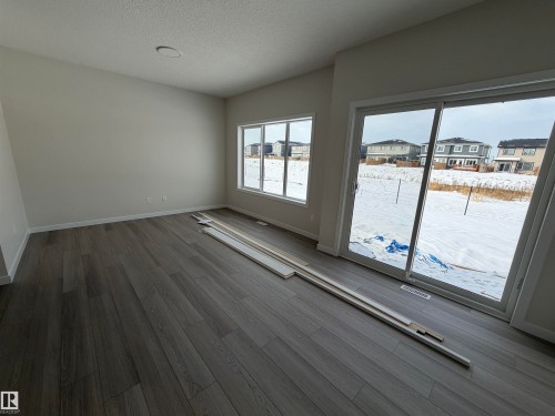 Unfurnished room featuring a residential view, wood finished floors, and a textured ceiling - 5756 Hawthorn Common, Edmonton, AB - Indoor Photo Showing Other Room