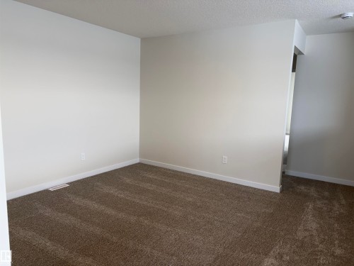 Unfurnished room with dark carpet and a textured ceiling - 5756 Hawthorn Common, Edmonton, AB - Indoor Photo Showing Other Room