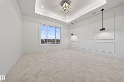 Carpeted spare room with a decorative wall, suspended lighting, and a tray ceiling - 4276 Charles Close, Edmonton, AB - Indoor Photo Showing Other Room