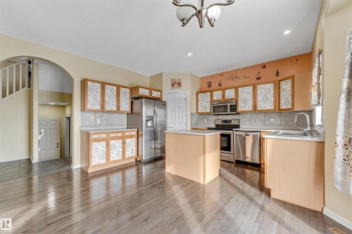 Kitchen featuring a kitchen island, tasteful backsplash, light countertops, stainless steel appliances, and arched walkways - 3449 28 Street, Edmonton, AB - Indoor Photo Showing Kitchen