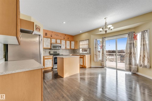 Kitchen with stainless steel appliances, light countertops, a center island, dark wood-style flooring, and a chandelier - 3449 28 Street, Edmonton, AB - Indoor Photo Showing Kitchen