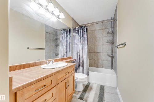 Bathroom featuring vanity, shower / bathtub combination with curtain, a textured ceiling, and light tile patterned flooring - 3449 28 Street, Edmonton, AB - Indoor Photo Showing Bathroom