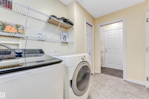 Laundry area with separate washer and dryer and light tile patterned flooring - 3449 28 Street, Edmonton, AB - Indoor Photo Showing Laundry Room