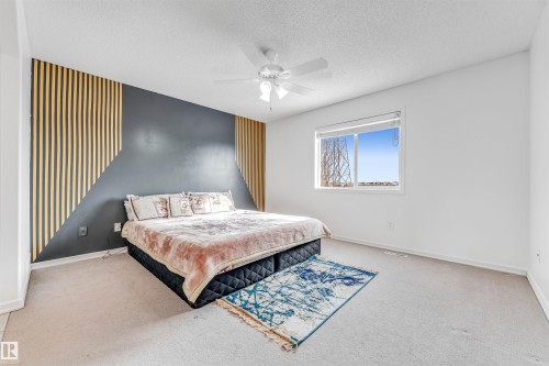 Bedroom with an accent wall, light carpet, a textured ceiling, and ceiling fan - 3449 28 Street, Edmonton, AB - Indoor Photo Showing Bedroom