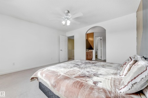 Bedroom with light colored carpet, a ceiling fan, arched walkways, ensuite bath, and a textured ceiling - 3449 28 Street, Edmonton, AB - Indoor Photo Showing Bedroom
