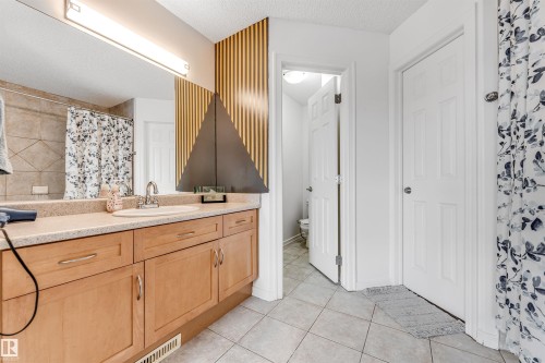 Bathroom featuring a textured ceiling, vanity, a shower with curtain, and light tile patterned floors - 3449 28 Street, Edmonton, AB - Indoor Photo Showing Bathroom