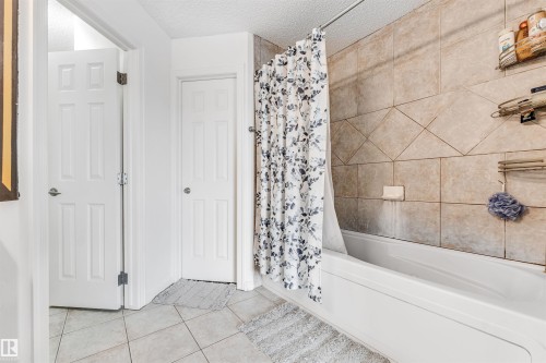 Bathroom featuring a textured ceiling, light tile patterned flooring, and shower / tub combo - 3449 28 Street, Edmonton, AB - Indoor Photo Showing Bathroom