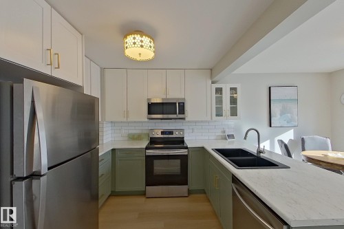 Kitchen with a peninsula, stainless steel appliances, decorative backsplash, glass insert cabinets, and two tone cabinetry - 121 1 Aberdeen Way, Stony Plain, AB - Indoor Photo Showing Kitchen With Stainless Steel Kitchen With Double Sink With Upgraded Kitchen