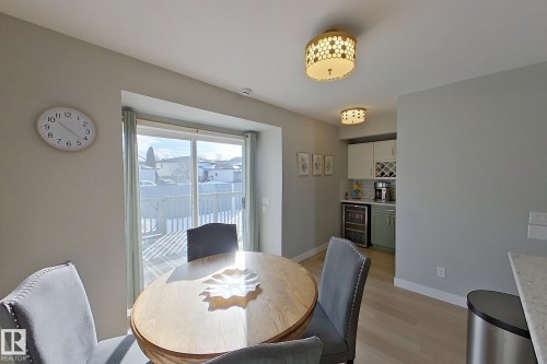 Dining area with light wood-style flooring, wine cooler, and a bar - 121 1 Aberdeen Way, Stony Plain, AB - Indoor Photo Showing Dining Room