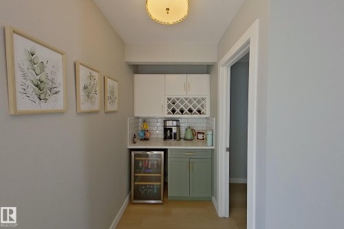Indoor dry bar with wine cooler, backsplash, light wood-type flooring, and two tone cabinets - 121 1 Aberdeen Way, Stony Plain, AB - Indoor Photo Showing Other Room
