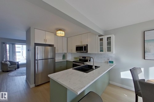 Kitchen featuring stainless steel appliances, tasteful backsplash, glass fronted cabinets, and a peninsula - 121 1 Aberdeen Way, Stony Plain, AB - Indoor Photo Showing Kitchen With Stainless Steel Kitchen With Double Sink With Upgraded Kitchen