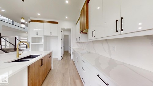 Kitchen featuring white cabinets, brown cabinetry, pendant lighting, light stone counters, and light wood-type flooring - 1707 18 Street, Edmonton, AB - Indoor Photo Showing Kitchen With Double Sink With Upgraded Kitchen