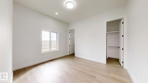 Unfurnished bedroom with light wood-type flooring and a walk in closet - 1707 18 Street, Edmonton, AB - Indoor Photo Showing Other Room