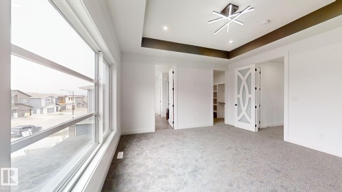 Unfurnished bedroom with a tray ceiling, a spacious closet, light carpet, and recessed lighting - 1707 18 Street, Edmonton, AB - Indoor Photo Showing Other Room