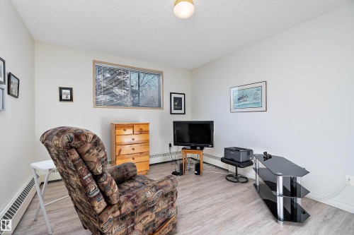 Living area featuring a textured ceiling, baseboard heating, and light floors - 116 11620 9A Avenue, Edmonton, AB - Indoor
