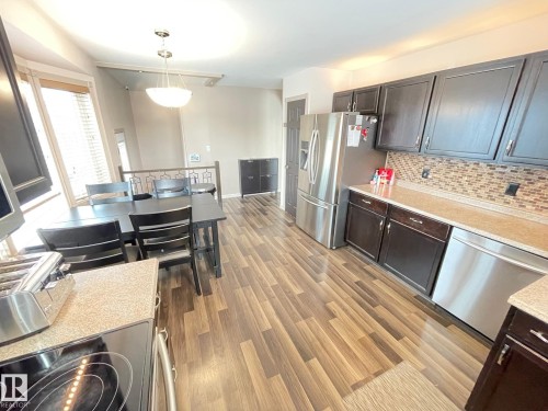 Kitchen with stainless steel appliances, light wood finished floors, pendant lighting, and dark wood finish cabinetry - 324 Warwick Road, Edmonton, AB - Indoor