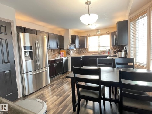 Kitchen featuring stainless steel appliances, hanging light fixtures, light countertops, and decorative backsplash - 324 Warwick Road, Edmonton, AB - Indoor