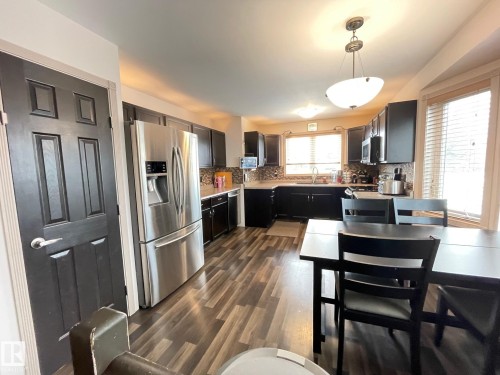 Kitchen featuring stainless steel appliances, tasteful backsplash, decorative light fixtures, and dark wood finished floors - 324 Warwick Road, Edmonton, AB - Indoor