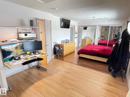 Bedroom with a textured ceiling, light wood-type flooring, track lighting, and a desk - 324 Warwick Road, Edmonton, AB - Indoor