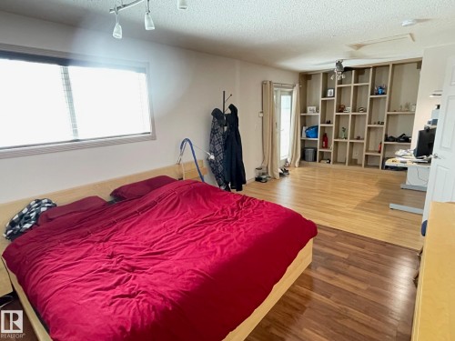 Bedroom featuring wood finished floors, a textured ceiling, and track lighting - 324 Warwick Road, Edmonton, AB - Indoor Photo Showing Bedroom