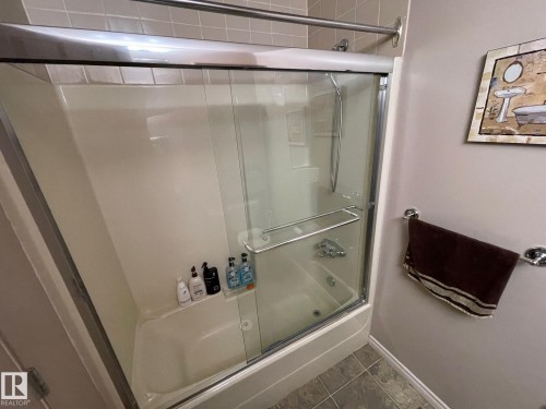 Full bathroom with combined bath / shower with glass door and dark tile patterned floors - 324 Warwick Road, Edmonton, AB - Indoor Photo Showing Bathroom