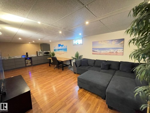 Living area featuring light wood-style flooring, a paneled ceiling, and wine cooler - 324 Warwick Road, Edmonton, AB - Indoor Photo Showing Basement