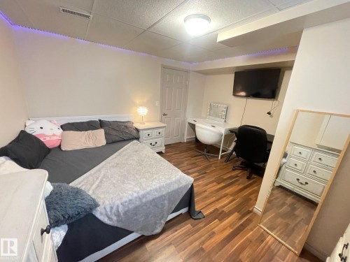 Bedroom in basement featuring dark wood finished floors, a drop ceiling, and an office area - 324 Warwick Road, Edmonton, AB - Indoor Photo Showing Bedroom