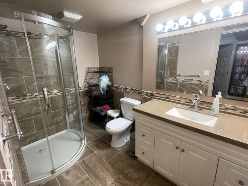 Bathroom featuring vanity, a stall shower, tile walls, and wainscoting - 324 Warwick Road, Edmonton, AB - Indoor Photo Showing Bathroom