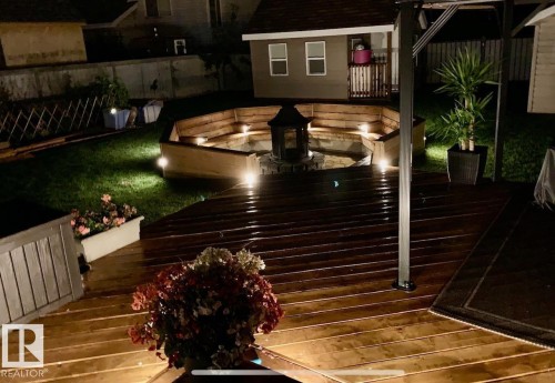 Deck at twilight that has fully lighting for entertaining and a fenced backyard, a storage shed, and outdoor dining space - 324 Warwick Road, Edmonton, AB - Outdoor With Exterior