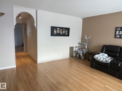 Living area featuring arched walkways, a textured ceiling, and light wood-type flooring - 324 Warwick Road, Edmonton, AB - Indoor Photo Showing Other Room