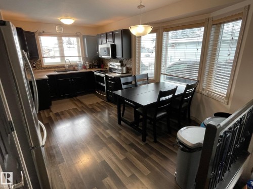 Kitchen with stainless steel appliances, light countertops, dark wood-style flooring, decorative backsplash, and pendant lighting - 324 Warwick Road, Edmonton, AB - Indoor Photo Showing Other Room
