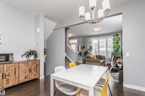 Dining area with dark wood finished floors and a chandelier - 16420 15 Avenue, Edmonton, AB - Indoor