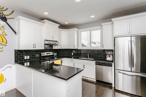 Kitchen with stainless steel appliances, dark stone counters, dark wood finished floors, a peninsula, and recessed lighting - 16420 15 Avenue, Edmonton, AB - Indoor Photo Showing Kitchen With Upgraded Kitchen