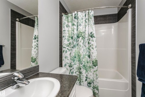 Full bathroom with a textured ceiling, shower / tub combo, and vanity - 16420 15 Avenue, Edmonton, AB - Indoor Photo Showing Bathroom