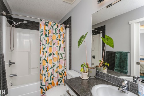 Full bathroom featuring vanity, a textured ceiling, shower / bath combination with curtain, and ensuite bathroom - 16420 15 Avenue, Edmonton, AB - Indoor Photo Showing Bathroom