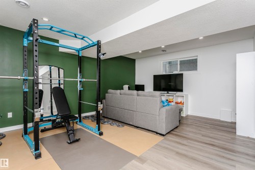 Workout area with a textured ceiling, light wood-type flooring, and recessed lighting - 16420 15 Avenue, Edmonton, AB - Indoor Photo Showing Gym Room