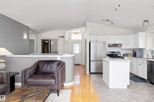 Kitchen featuring a kitchen island, stainless steel appliances, light countertops, white cabinets, and light wood-style floors - 357 Blackburn Drive E, Edmonton, AB - Indoor Photo Showing Kitchen